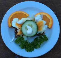 Smiley smørrebrød med æg, agurk, mayonnaise, appelsin og persille